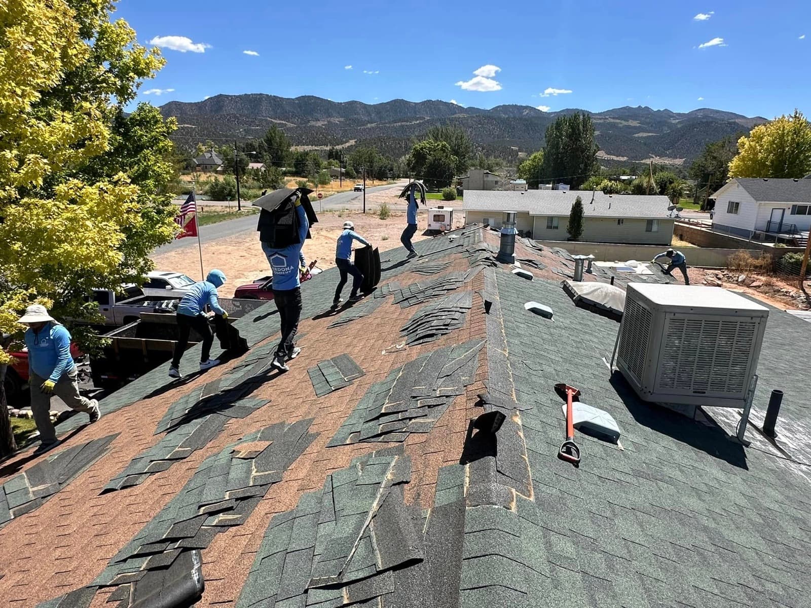 Cardona Company crew tearing off an old roof with the mountains of Southern Utah behind them