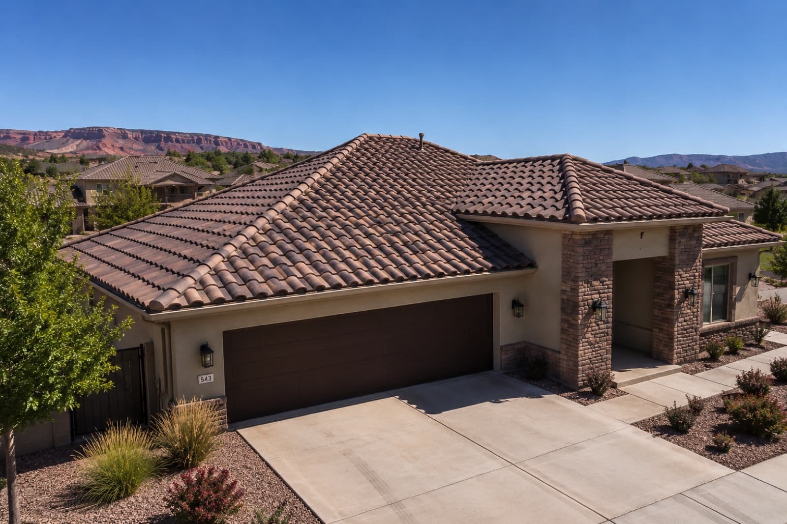 Finished brown Spanish-tile roof on a Southern Utah home framed by red-rock cliffs