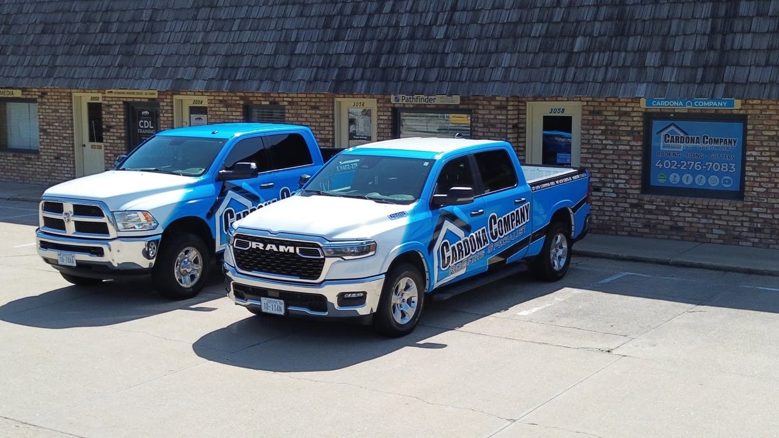 Cardona Company Roofing Specialist fleet of two branded trucks parked at the office