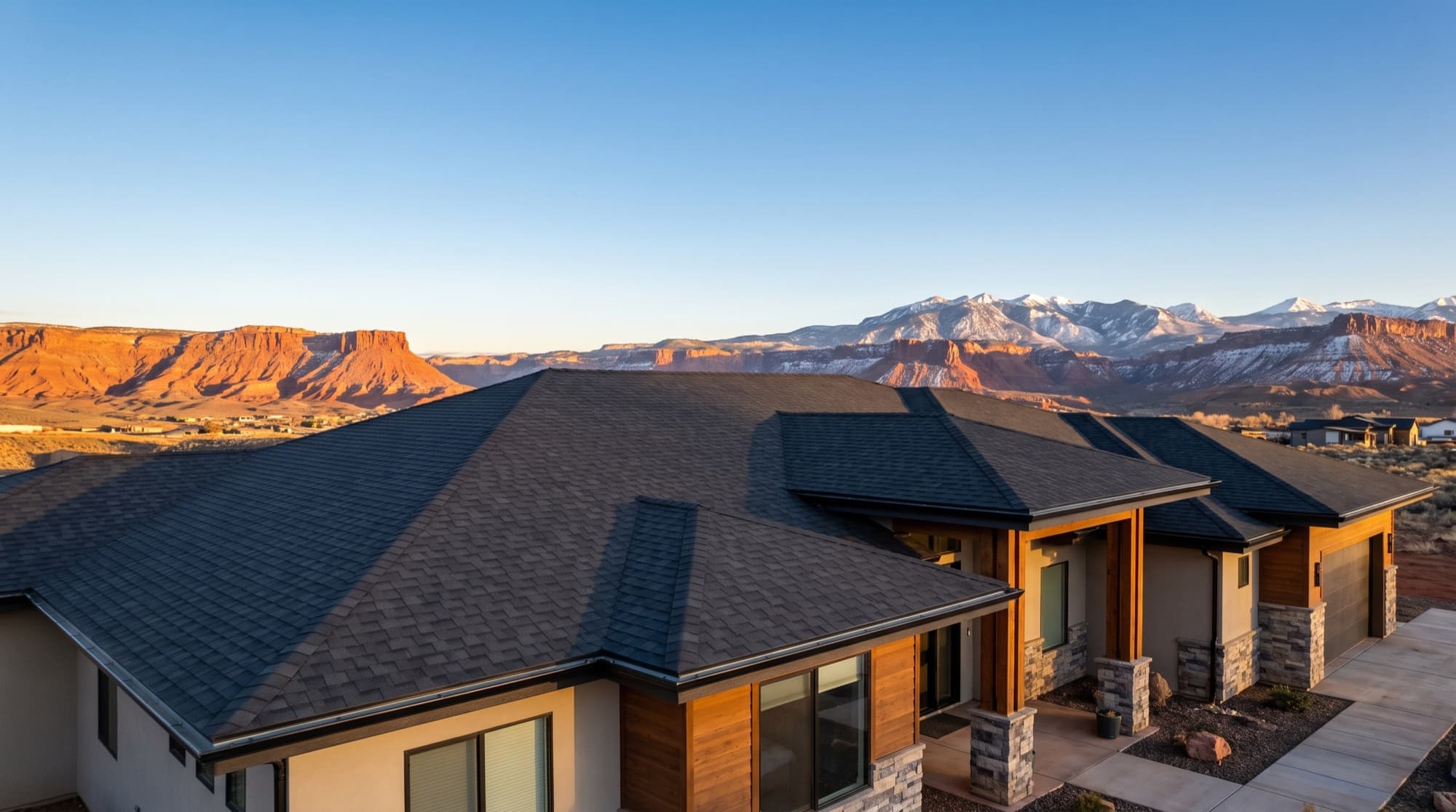Close-up of a new dark charcoal shingle roof on a Southern Utah home with red rock and mountains behind